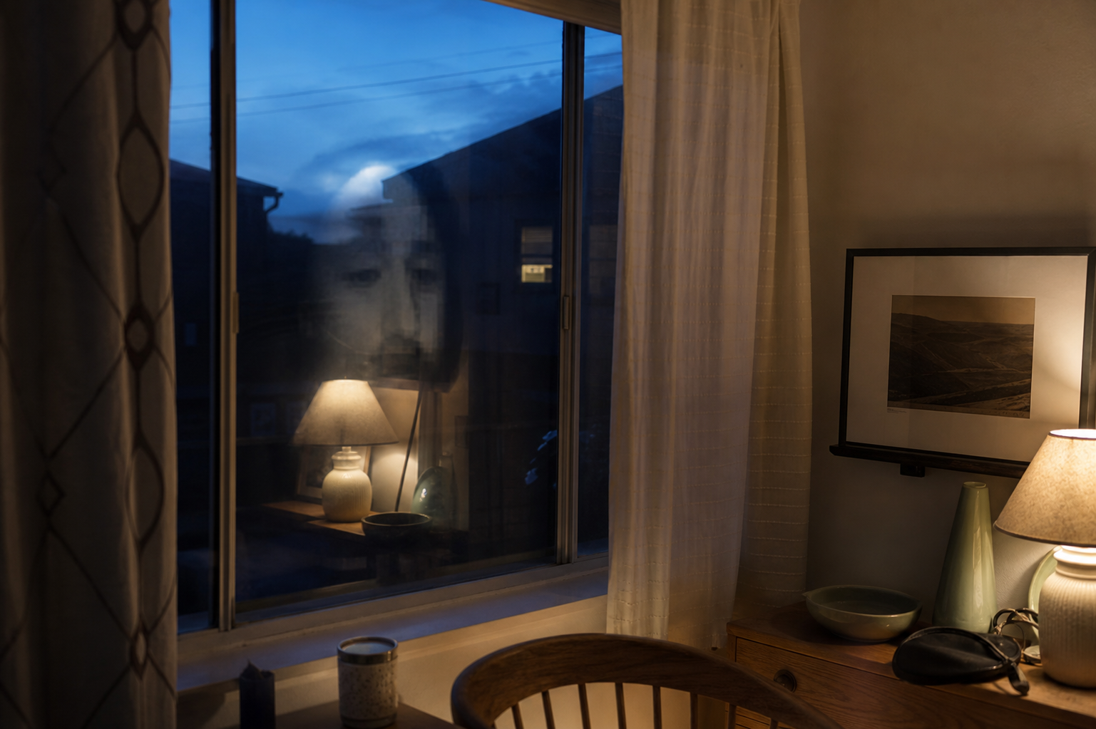 A controlled reconstruction showing how a lamp, room objects and layered glass reflections can combine into a face-like pattern. It is an interpretive demonstration, not the reported photograph.